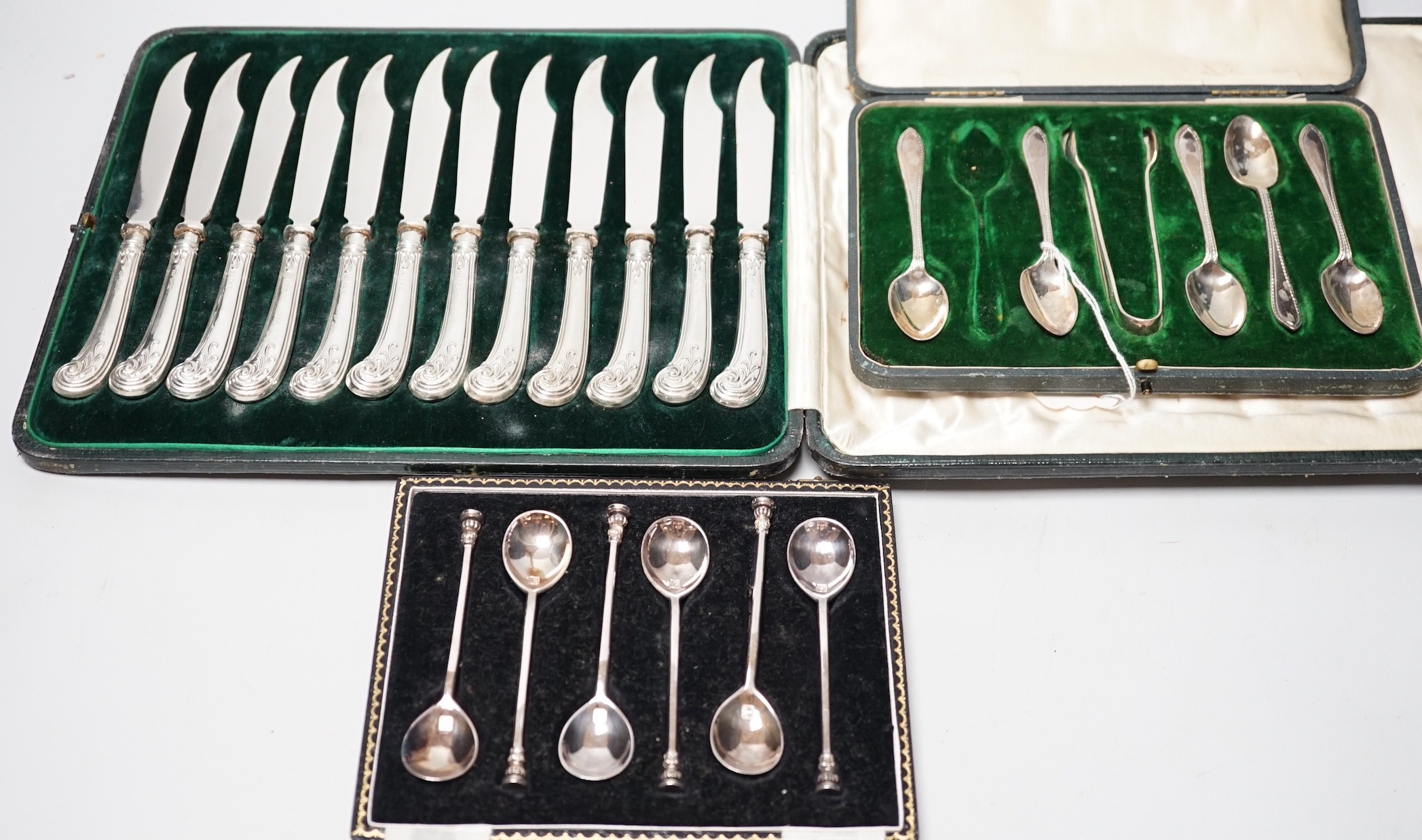 A cased set of twelve silver handled dessert knives, six seal-top teaspoons, five (ex 6) teaspoons and tongs.